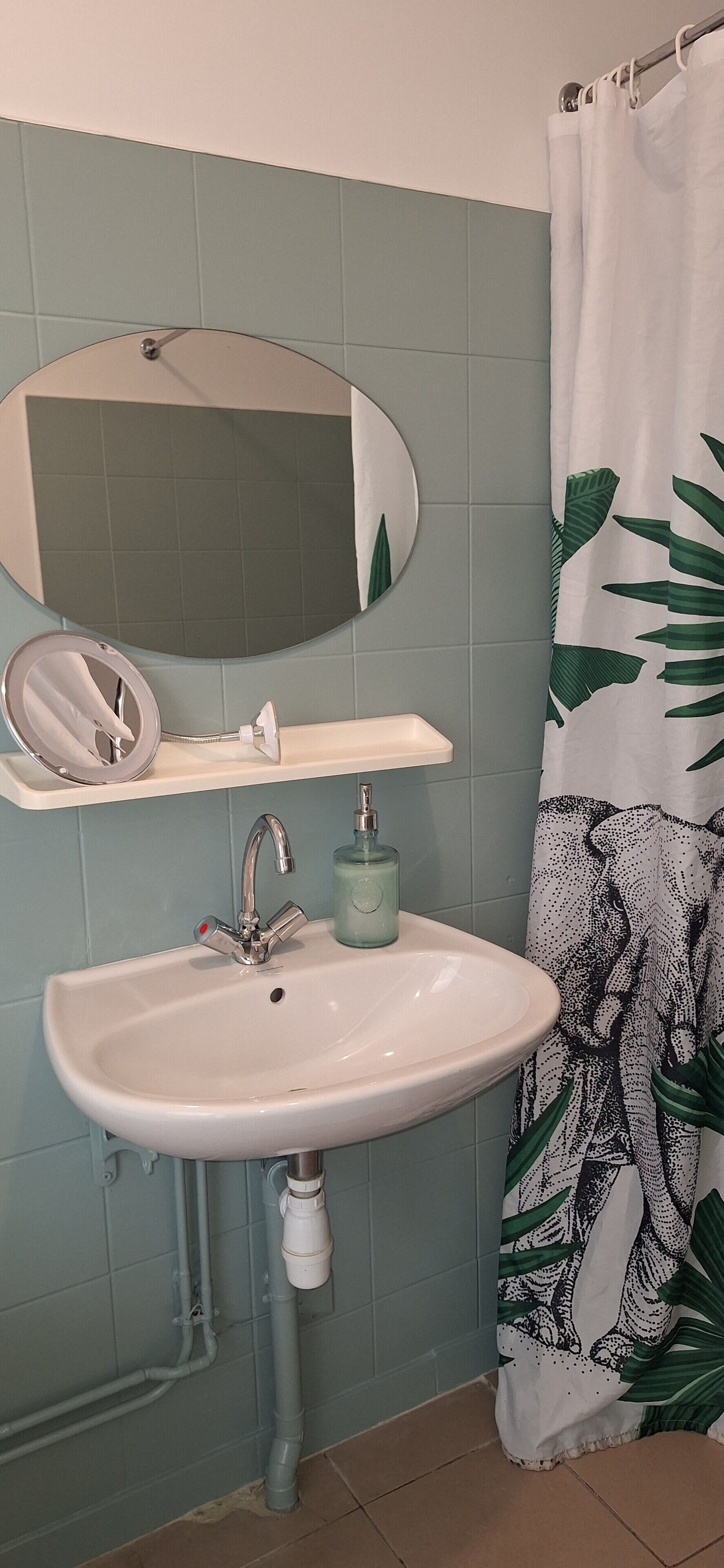 Un baño con lavamanos, espejo y cortina de ducha.