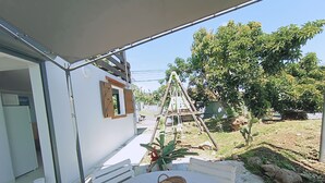 An outdoor patio with a round table, a wicker basket, and a white chair. - O'Romarin | Sea & rivers - Chutes du Carbet (Capesterre-Belle-Eau)