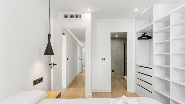 A modern hotel room with a bed, a walk-in closet, and a hallway leading to a bathroom. - Apartment 'La Siesta 5' with Shared Pool, Wi-Fi and Air Conditioning (Fuengirola)