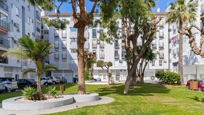 A residential building with balconies, a well-maintained lawn, and parked cars. - Apartment 'La Siesta 5' with Shared Pool, Wi-Fi and Air Conditioning (Fuengirola)