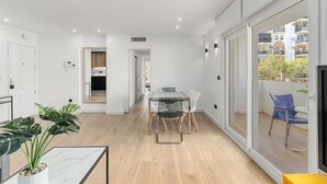A modern apartment with a dining area, a balcony with a view, and a kitchen in the background. - Apartment 'La Siesta 5' with Shared Pool, Wi-Fi and Air Conditioning (Fuengirola)