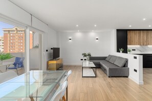 A modern apartment with a glass dining table, a grey sofa, and a kitchen area with wooden cabinets. - Apartment 'La Siesta 5' with Shared Pool, Wi-Fi and Air Conditioning (Fuengirola)