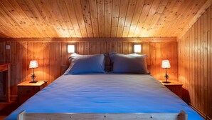 Ein Zimmer mit Holzvertäfelung, einem Bett, zwei Nachttischen und zwei Wandleuchten.