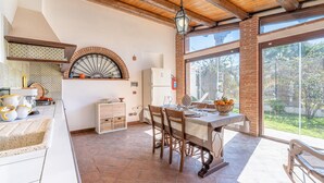 Uma cozinha com área de refeições, forno de tijolos e janelas grandes.