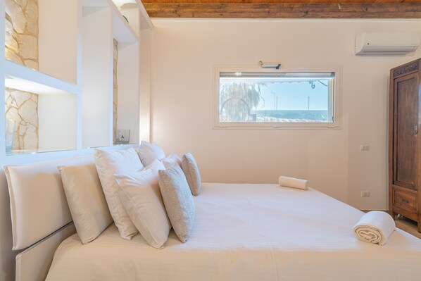 A bedroom with a bed, pillows, a window, and a wooden cabinet.