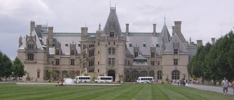 A large, historic building with a symmetrical facade, multiple chimneys, and a central tower.