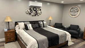 A modern bedroom with a large bed, two bedside tables, a grey sofa, and a decorative wall piece. - Bright New 1 bedroom Retreat (Candler)