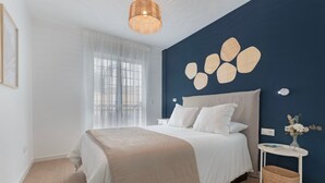 Una camera da letto con un letto, un comodino, un'opera d'arte a parete e una finestra con tende.