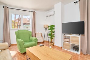 A living room with a green armchair, a wooden coffee table, a TV on a stand, a lamp, and a potted plant. - Apartment 'Los Cactus' with Balcony, Wi-Fi and Air Conditioning (Almuñécar)