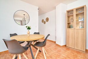 A dining area with a round table, chairs, a mirror, wall decorations, and a wooden cabinet.