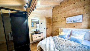 Une chambre à coucher avec un lit, des tables de chevet, un miroir et un mur en bois.