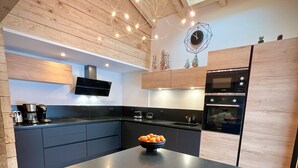 Une cuisine moderne dotée d’un îlot central, de meubles en bois et d’un four encastré.