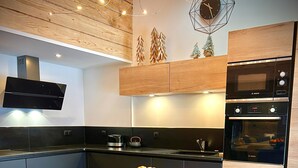 Une cuisine moderne dotée d’un îlot central en bois, d’appareils électroménagers de la marque Bosch et d’une horloge décorative.