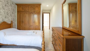A bedroom with a large bed, wooden wardrobe, dresser, and a mirror. - Country House 'Casa Da Carballeira' with Mountain View, Private Garden and Wi-Fi (A Estrada)