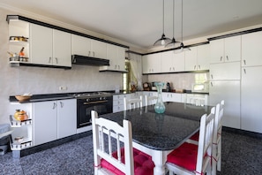 A modern kitchen with white cabinets, a granite countertop, and a dining table with white chairs.