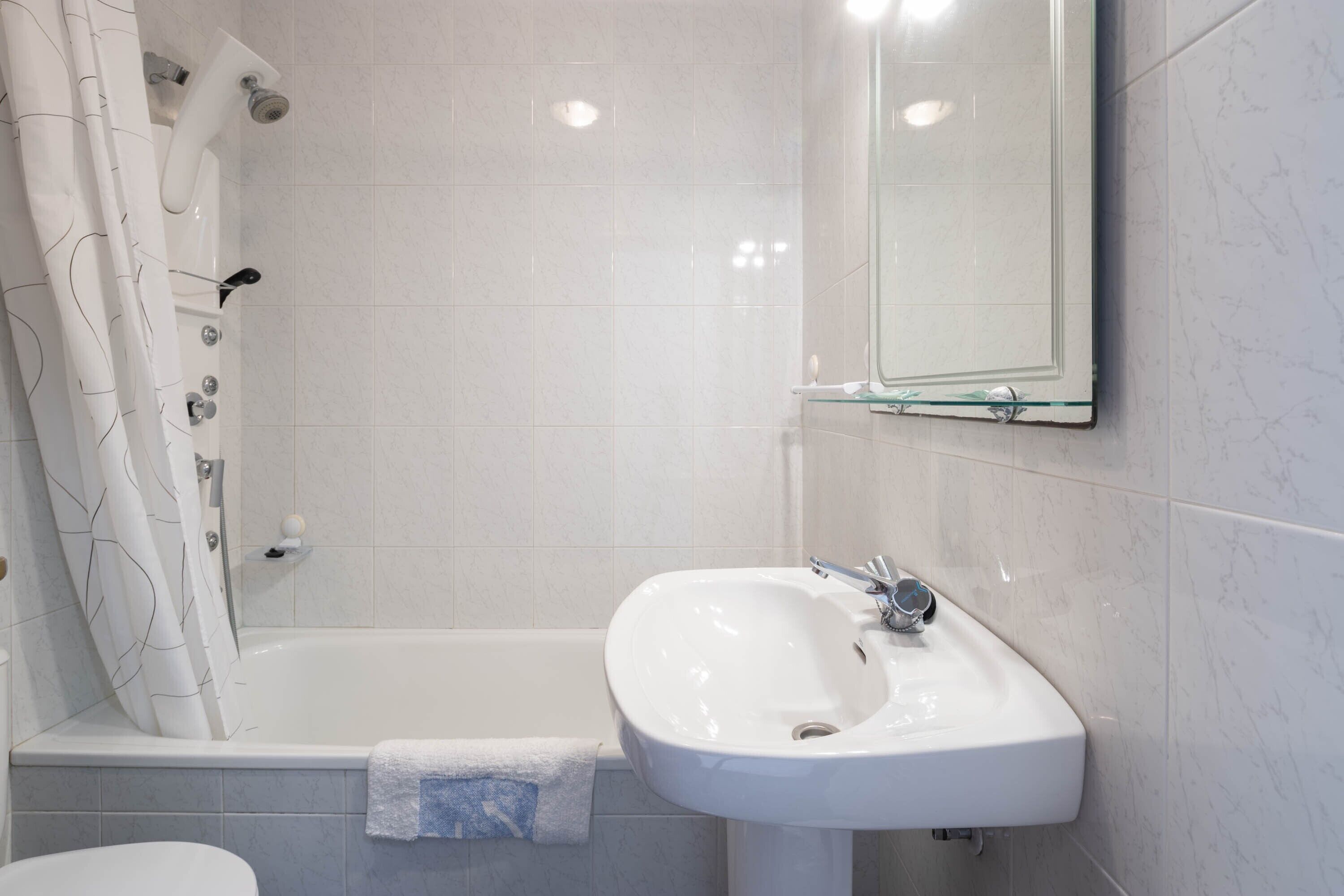 A bathroom with a bathtub, a sink, and a mirror.