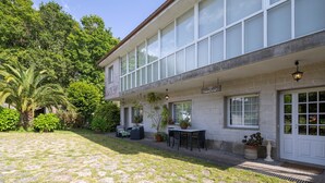 A two-story building with a stone facade, large windows, and a covered patio area with outdoor seating. - Country House 'Casa Da Carballeira' with Mountain View, Private Garden and Wi-Fi (A Estrada)