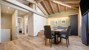 Ein Essbereich mit Holztisch und Stühlen, einer Couch und Bildern an der Wand.