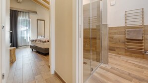 Ein modernes Badezimmer mit Glasdusche, Holzboden und Handtuchhalter.