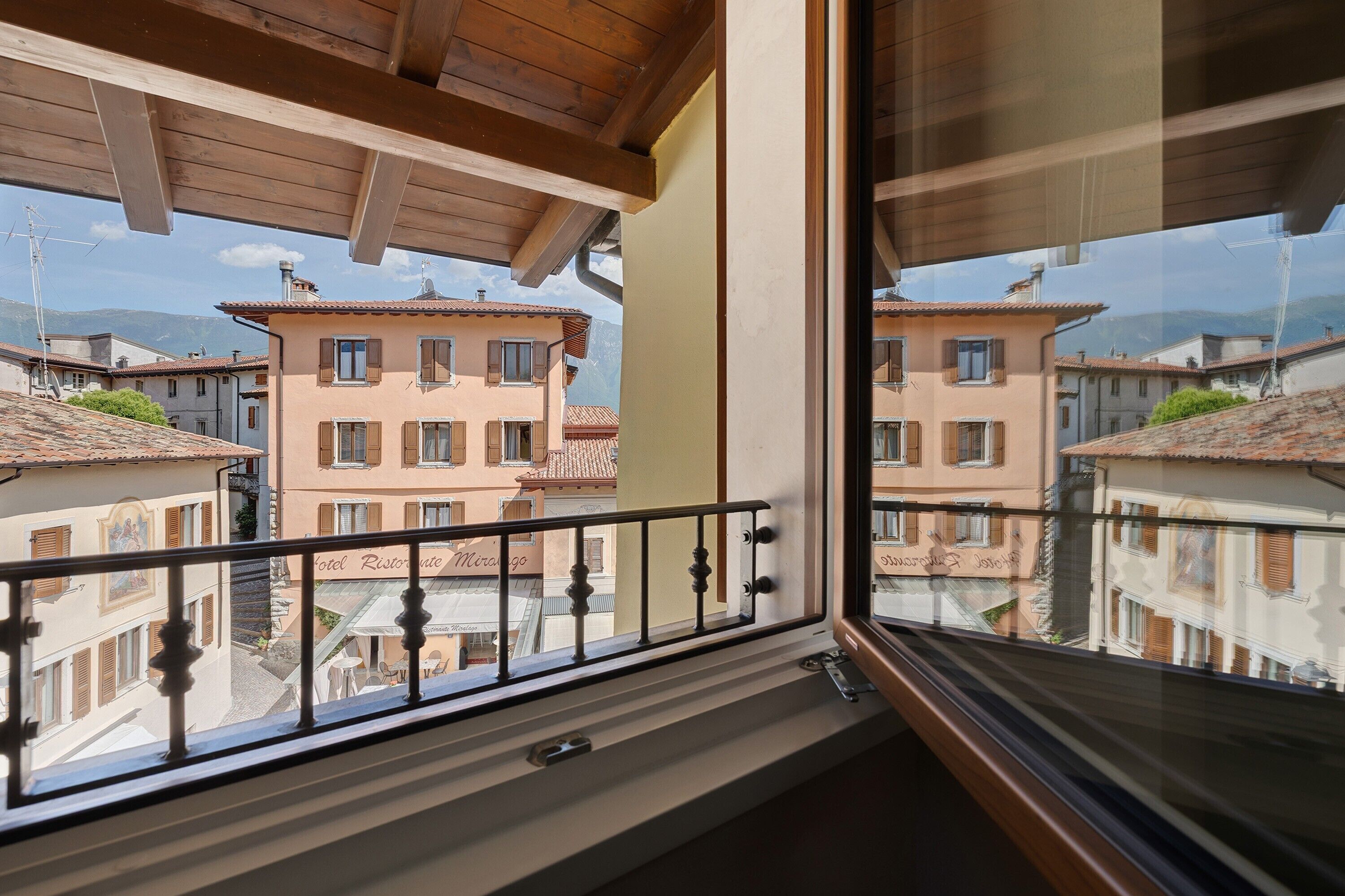 A balcony with a wooden ceiling, a metal railing, and a view of neighboring buildings.