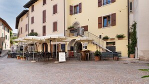Ein Kopfsteinpflasterhof mit Außenbestuhlung, einer Treppe und einem Gebäude mit zahlreichen Fenstern und Balkonen.