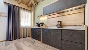 Eine moderne Küche mit dunklen Marmor-Schränken, Holzböden und einem Fenster mit Vorhängen.