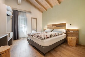 A bedroom with a bed, bedside table, and a small wooden stool.