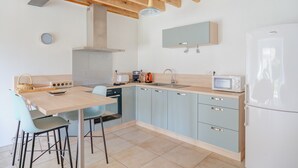 A modern kitchen with a wooden ceiling, a sink, a microwave, and a refrigerator. - Holiday Home 'La Ferme D'Alcide' with Private Terrace, Private Garden and Wi-Fi (Québriac)