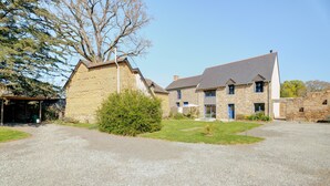 A stone building with a gravel driveway, a small lawn, and a tree. - Holiday Home 'La Ferme D'Alcide' with Private Terrace, Private Garden and Wi-Fi (Québriac)