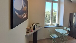 A kitchen with a window, a table with chairs, a refrigerator, and a wall-mounted picture.