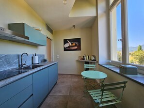 Een compacte keuken met een spoelbak, aanrecht en een klein eethoekje met een tafel en stoelen.