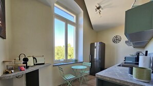 A compact kitchen with a window, a refrigerator, a sink, and a small dining area.