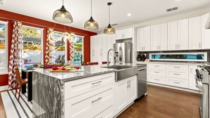 A modern kitchen with white cabinets, a large island, stainless steel appliances, and pendant lighting. - Heated Pool, MiniGolf, Karaoke, Game Room, Spa, 2mi to DT - SoCo Cowgirl (Austin)