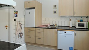 A compact kitchen with a refrigerator, microwave, dishwasher, and wooden cabinets. - 1 bedroom beautiful home in Højer (Højer)