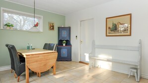A dining room with a wooden table and chairs, a cabinet with floral decorations, and a framed picture on the wall. - 1 bedroom beautiful home in Højer (Højer)