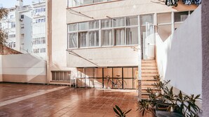 Um pátio com piso de azulejos, uma bicicleta e plantas em vasos.