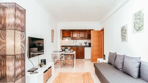 Uma sala de estar moderna com um sofá cinzento, uma mesa de centro e uma TV fixada na parede.