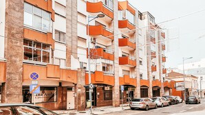 A multi-story building with orange balconies and a parking area in front. - Amadora Terrace View By Gt House (Amadora)