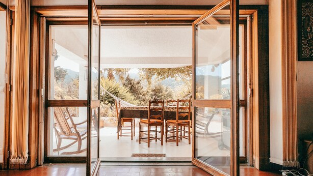 Una habitación con puerta corrediza de vidrio que da a un patio exterior con mesa y sillas.