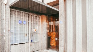A gated entrance with a metal gate and a glass door, leading to a building with a tiled interior. - Giestal Terrace By GT House (Lisbon)