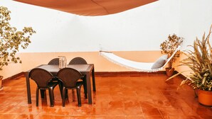 A patio with a table and chairs, a hammock, and potted plants. - Giestal Terrace By GT House (Lisbon)
