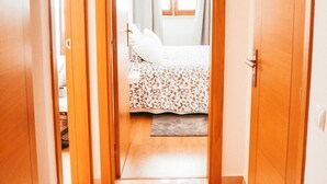 A narrow hallway leading to a bedroom with a bed, curtains, and a window. - Giestal Terrace By GT House (Lisbon)