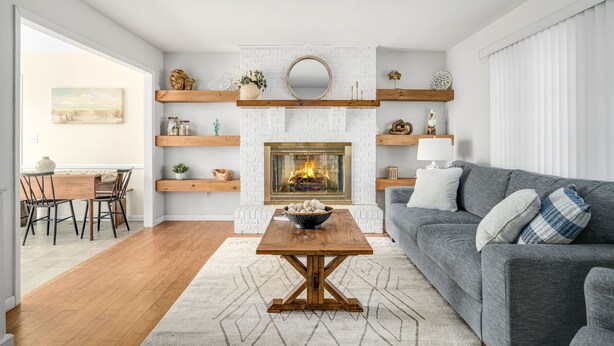 Una sala de estar moderna con chimenea, estanterías de madera y un sofá gris.