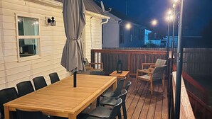 Una terraza al aire libre con una mesa y sillas de madera, un espacio de estar cubierto y una barra.
