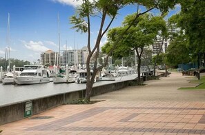 A marina with boats docked, a waterfront promenade, and a building in the background. -  Studio apartment with City Views (Kangaroo Point)