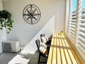 A sunlit room with a table and chairs, a wall-mounted compass decoration, and a window with blinds. -  Studio apartment with City Views (Kangaroo Point)