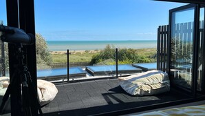 A balcony with a telescope, a covered seating area, and a view of the beach.