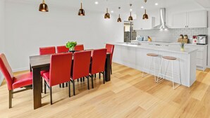 Una cocina moderna con una isla central, sillas rojas e iluminación colgante.