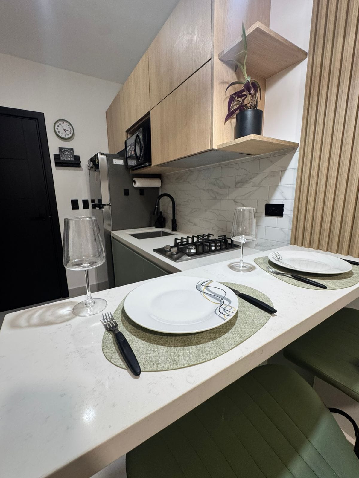 Een moderne keuken met een marmeren aanrechtblad, een inbouwmagnetron en een gasfornuis.
