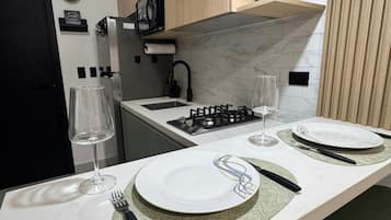 Een moderne keuken met een marmeren aanrechtblad, een inbouwmagnetron en een gasfornuis.